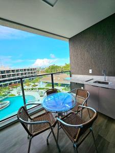 a glass table and two chairs on a balcony at Luxuoso e sofisticado Beach Class Verano by HM in Ipojuca
