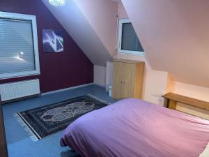 a bedroom with purple walls and a bed and a rug at Chez Corinne et Michel in Saasenheim