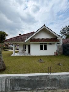 a white house with a grass yard in front of it at Villa puncak 3 room in Cikundul
