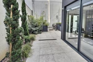 a sidewalk with trees and plants next to a building at 50m2 côté Bâle parking inclus in Saint-Louis