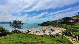 a beach with a group of people sitting on the sand at Casa Kitnet Loft Bidu House in Imbituba +31 photos