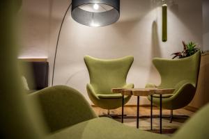 a waiting room with green chairs and a table at Hotel La Fradora - Dolomites Hotel in San Cassiano