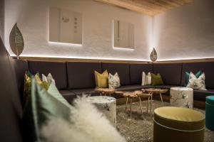 a living room with a couch and tables and pillows at Hotel La Fradora - Dolomites Hotel in San Cassiano