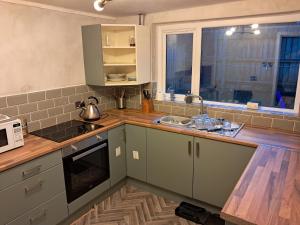 a kitchen with green cabinets and a sink and a window at Entire House in Belfast