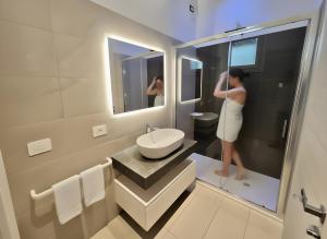 a woman standing in a bathroom looking in the mirror at Hotel Belvedere in Sottomarina +59 photos
