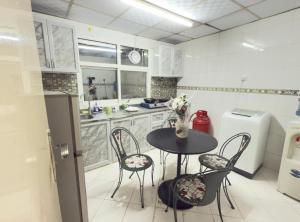a kitchen with a table and chairs and a refrigerator at Stay home in ‘Uqayr