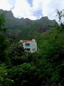 a house on a hill with mountains in the background at ROMANA guest house in Tarrafal da Vila de Ribeira Grande