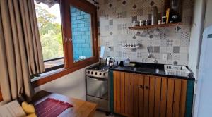 a kitchen with a stove and a sink and a window at Casa Kitnet Loft Bidu House in Imbituba