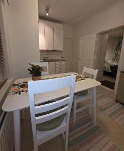 a white kitchen with a white table and chairs at Huoneisto Kuusi in Kokkola +5 photos