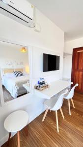 a white room with a bed and a desk and chairs at Casa da Praia Pousada in Torres