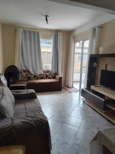 a living room with a couch and a tv at Casa da Cissa in Matinhos