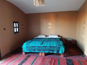 a bedroom with a bed with a blue comforter at Sahara Peace in Mhamid