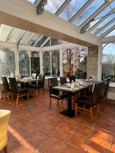 a conservatory with tables and chairs and windows at The Dog & Partridge Country Inn in Ashbourne