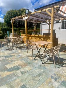 a patio with tables and chairs under a pergola at Vanille-colibris Le Domaine Mannou in Sainte-Rose