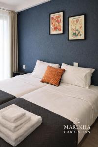 a large bed with white sheets and an orange pillow at Marinha Garden Inn - AL in Marinha Grande +29 photos