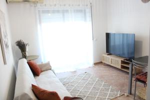 a living room with a white couch and a tv at Alojamento Bem-me-quer in Reguengos de Monsaraz