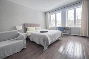 a white bedroom with two beds and a couch at Quiet Private Master Suite w Ensuite Great Value in Bélanger