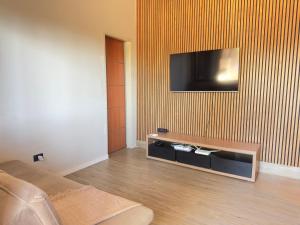 a living room with a flat screen tv on a wall at Caminho do mar in Itanhaém +7 photos