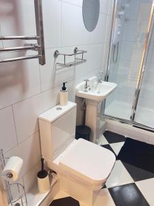 a white bathroom with a toilet and a sink at Little B - Artist owned boutique apartment near Southsea beach in Portsmouth