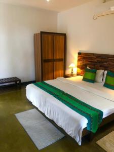 a bedroom with a large white bed with green accents at Nature Luxe Sigiriya in Sigiriya +42 photos