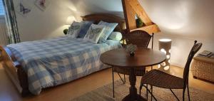 a bedroom with a bed and a table and chairs at Maison des Hortensias in Saint-Contest