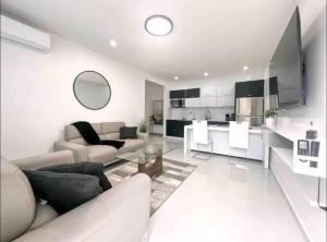 a white living room with a couch and a kitchen at Isabela Luxury Escape Serenity in Isabela