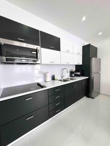 a kitchen with black cabinets and a stainless steel refrigerator at Isabela Luxury Escape Serenity in Isabela