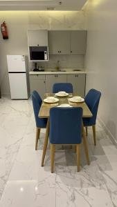 a kitchen with a table and blue chairs in a kitchen at شقق مخدومه in Ash Shafa