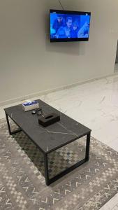 a black coffee table in front of a tv at شقق مخدومه in Ash Shafa