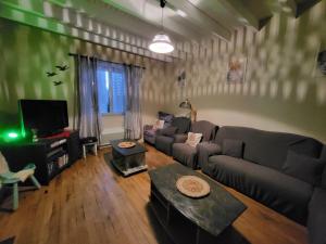 a living room with a couch and a tv at Au doux refuge in Saint-Exupéry-les-Roches