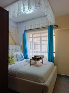 a bedroom with a white bed with blue curtains at Atis Smart Stay in Kisumu