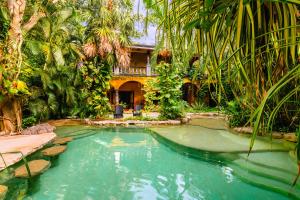 a swimming pool in front of a house with palm trees at La Hacienda Hotel, at Xcaret in Playa del Carmen