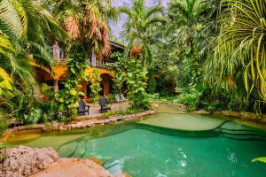 a swimming pool in front of a house with palm trees at La Hacienda Hotel, at Xcaret in Playa del Carmen