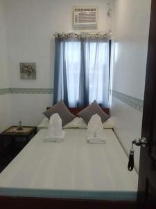 a bedroom with a large white bed with a window at Fil-Can Hostel Coron in Coron +45 photos