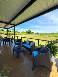 a deck with chairs and tables and a view of a field at Villa Morivivi Couples with pool in Tierras Nuevas Poniente