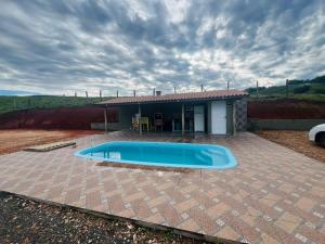a swimming pool in front of a small house at Pousada Helena e Heloá in Serra Negra