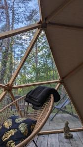 a wicker chair with a hat sitting in a tent at Arborea, nuits insolites au cœur de la forêt in Montignac