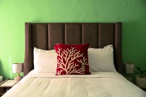 a bed with a red pillow and a green wall at Luxe Residence Guest House in Kasane