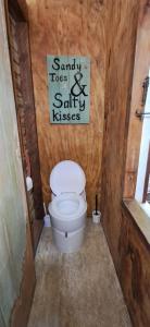 a bathroom with a toilet and a sign on the wall at The Clearing - Rustic Wagon by the Sea in Picton +30 photos