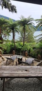 a wooden bench with palm trees in the background at The Clearing - Rustic Wagon by the Sea in Picton