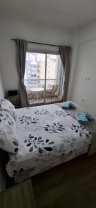 a bedroom with a bed with a comforter and a window at ADS DEPARTAMENToS 2 in La Plata