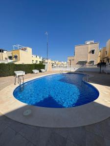 a large pool with blue water in a courtyard at Rekkehus med uteplass in La Florida