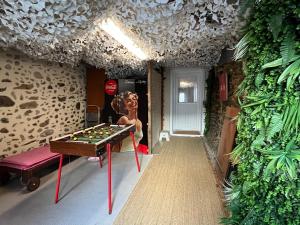 a room with a pool table and a woman standing next to a wall at La cachette chic ! in Sainte-Hélène-du-Lac