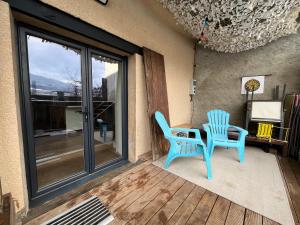 a patio with two blue chairs and a table at La cachette chic ! in Sainte-Hélène-du-Lac