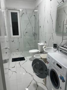 a white bathroom with a washing machine in it at Apartment Elis in Kamëz +21 photos
