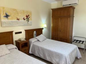 a hotel room with two beds and a cabinet at Hotel Los Desmontes in Membrilla
