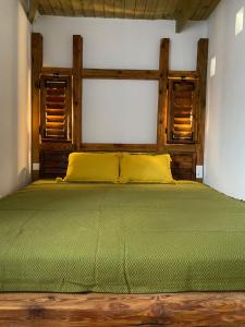 a bedroom with a green bed with two windows at Colonia Natura Apartmanpark in Sitke