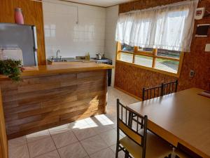 a kitchen with a counter and a table and a refrigerator at Agroturismo Coñico in Quilquico