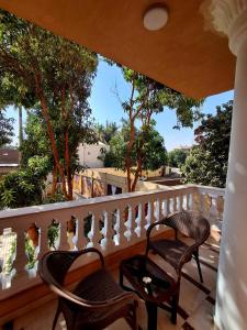 two chairs on a balcony with trees in the background at El Agamy Hotel Apartment in Luxor