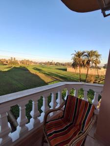 a chair on a balcony looking out at the golf course at El Agamy Hotel Apartment in Luxor